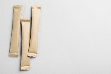 Photo of Beige sticks of sugar on light grey background, flat lay. Space for text