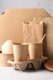 Photo of Eco friendly food packaging. Paper containers, tableware and bag on light background