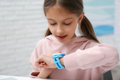 Photo of Girl with stylish smart watch at table indoors