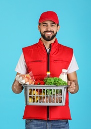 Photo of Man holding basket with fresh products on color background. Food delivery service