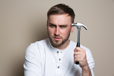 Photo of Young working man with hammer on beige background