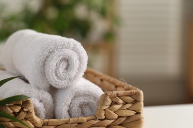 Photo of Spa composition. Towels in wicker basket indoors, closeup. Space for text