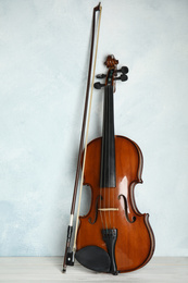 Photo of Beautiful violin and bow on white wooden table near light blue wall