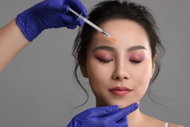 Photo of Woman getting facial injection on grey background