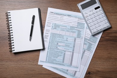 Photo of Payroll. Tax return forms, calculator, notebook and pen on wooden table, flat lay