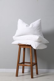 Photo of Soft pillows on chair neal light grey wall indoors