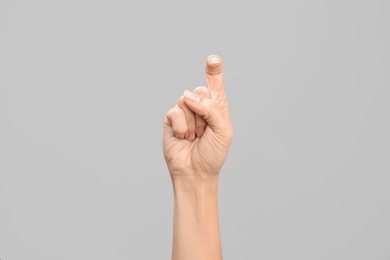 Photo of Woman showing X letter on grey background, closeup. Sign language