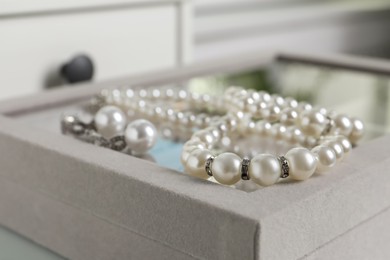 Photo of Luxurious pearl necklace and earrings on jewelry box, closeup