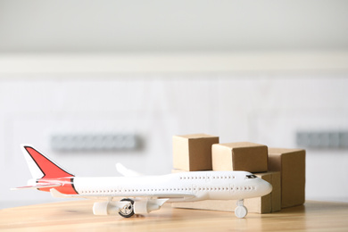 Photo of Toy plane and cardboard boxes on table against blurred background, space for text. Courier service