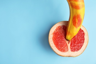 Photo of Flat lay composition with fresh banana and grapefruit on blue background, space for text. Sex concept