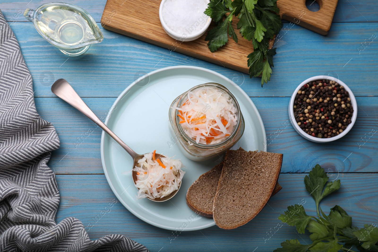 Photo of Tasty sauerkraut and ingredients on light blue wooden table, flat lay