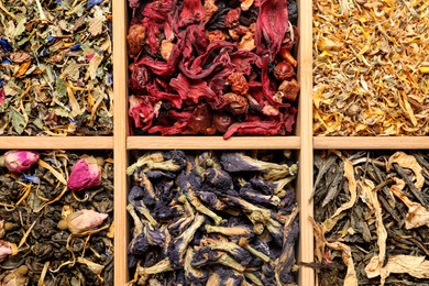 Photo of Different dry herbal teas in wooden box, top view