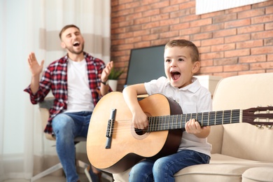 Photo of Father and son playing guitar and singing at home