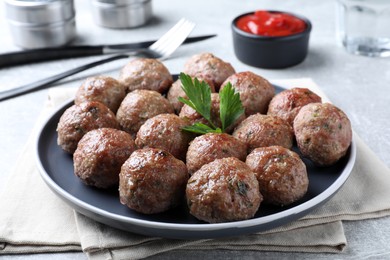 Photo of Tasty cooked meatballs with parsley on light grey table, closeup