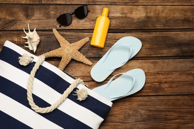 Photo of Stylish bag and beach accessories on wooden background, flat lay