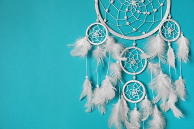 Photo of Beautiful dream catcher hanging on light blue background. Space for text