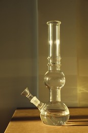 Glass bong on wooden table indoors. Smoking device