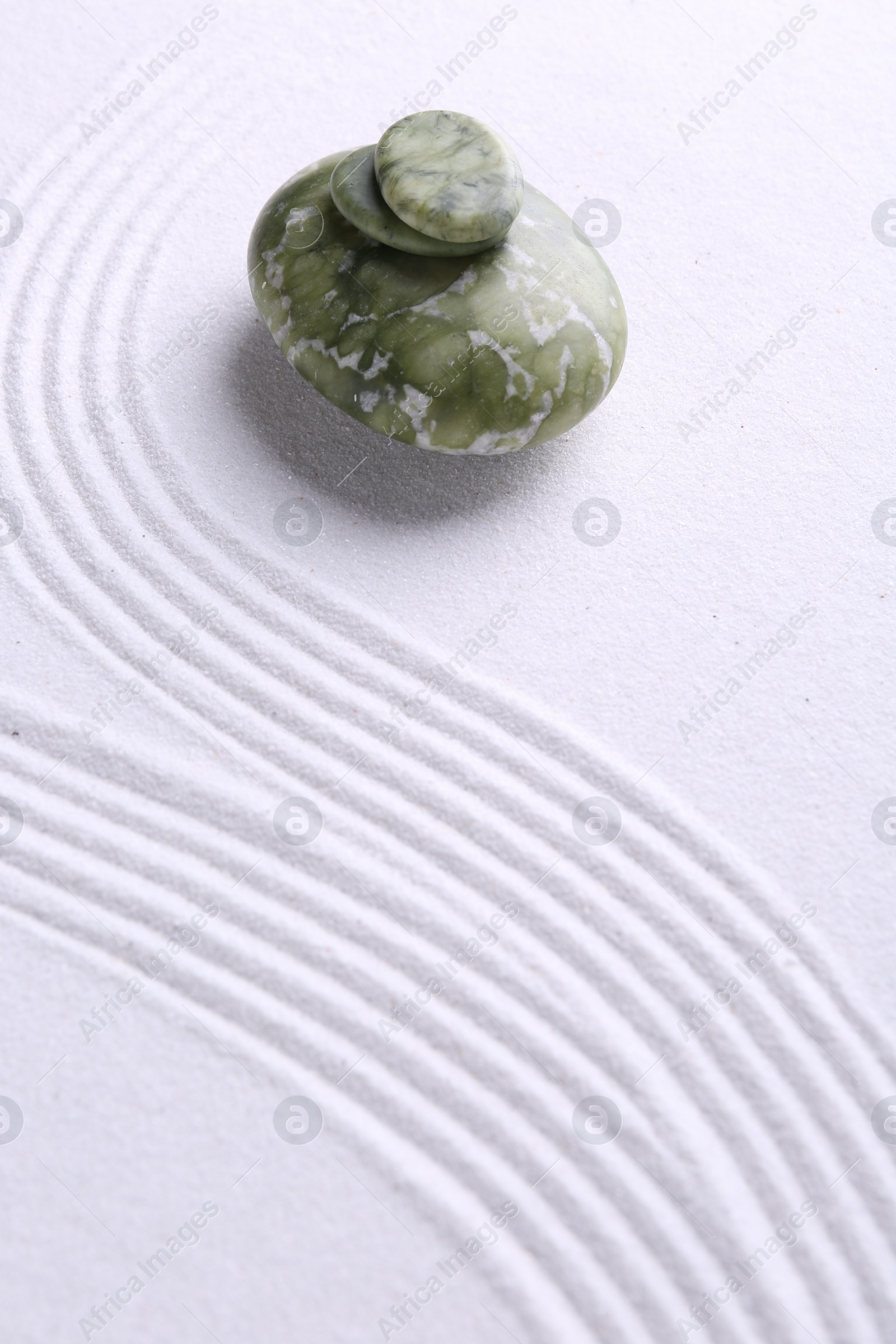 Photo of Zen garden stones on white sand with pattern. Space for text