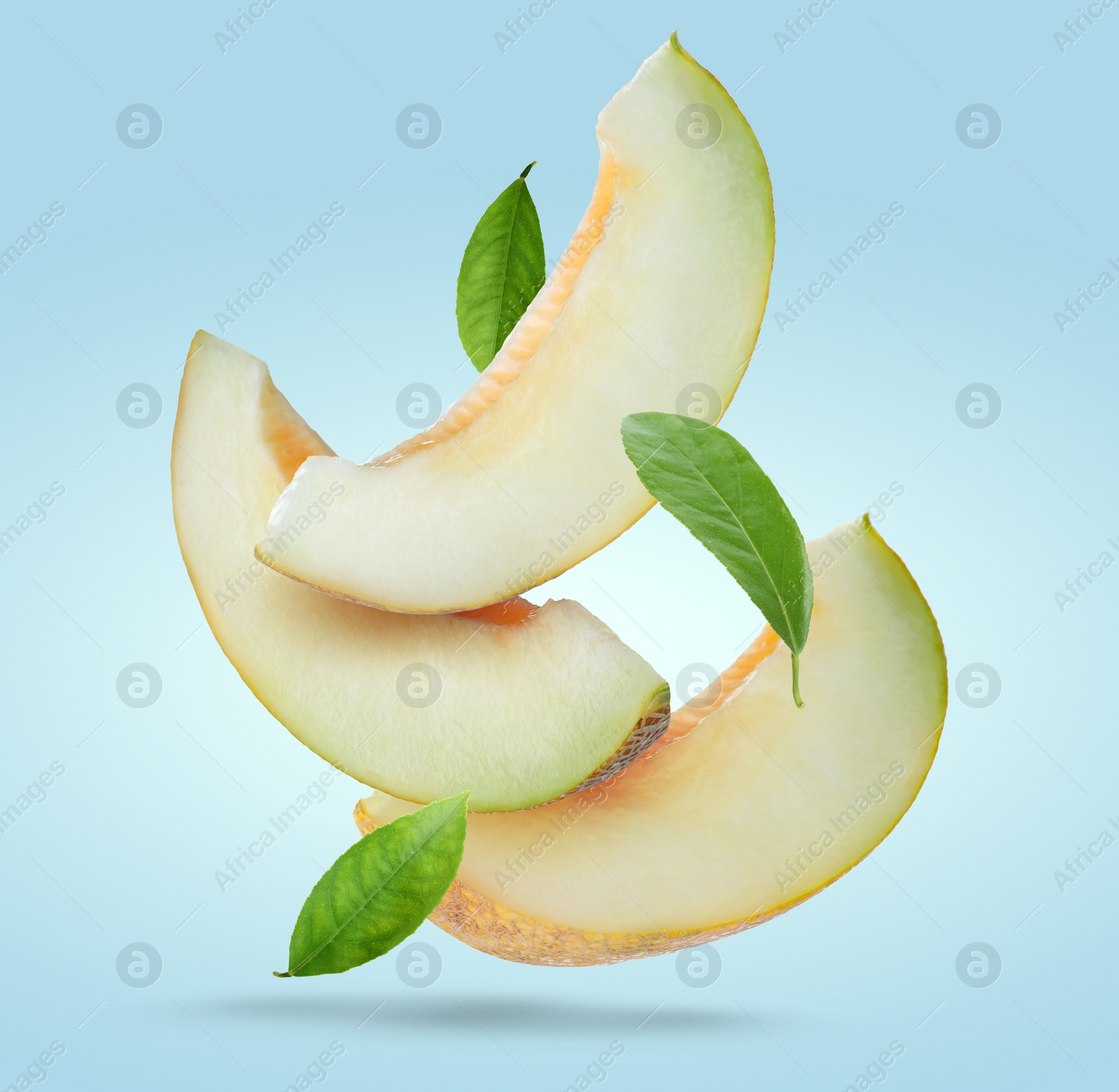 Image of Delicious ripe melon slices and leaves falling on pale light blue background