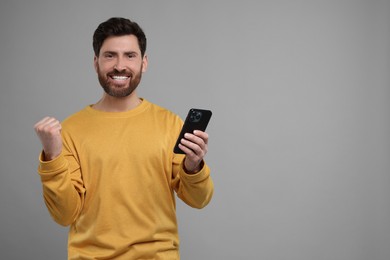 Photo of Smiling man with smartphone on grey background. Space for text