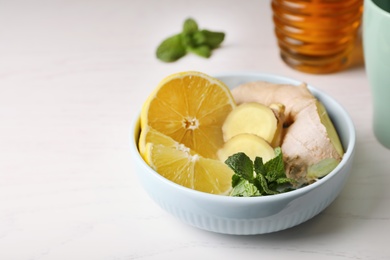 Photo of Bowl with lemon, ginger and mint on table, space for text. Cough remedies