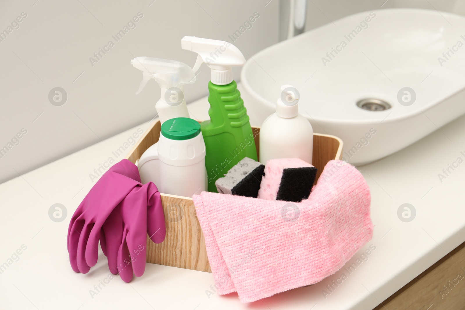 Photo of Different cleaning products in wooden box on countertop indoors