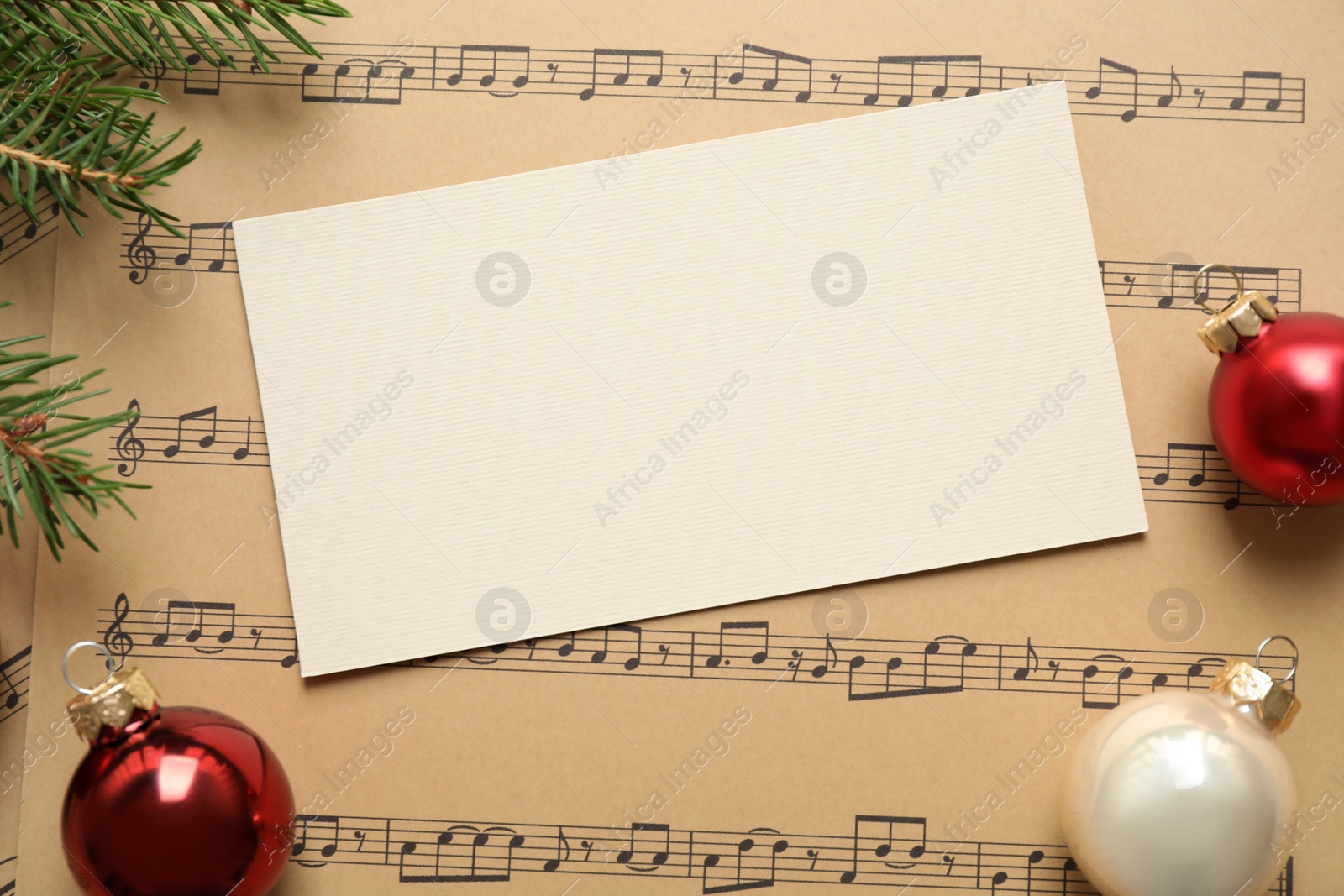 Photo of Flat lay composition with Christmas decorations and blank card on music sheets, space for text