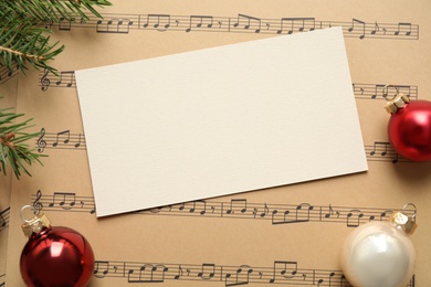 Flat lay composition with Christmas decorations and blank card on music sheets, space for text