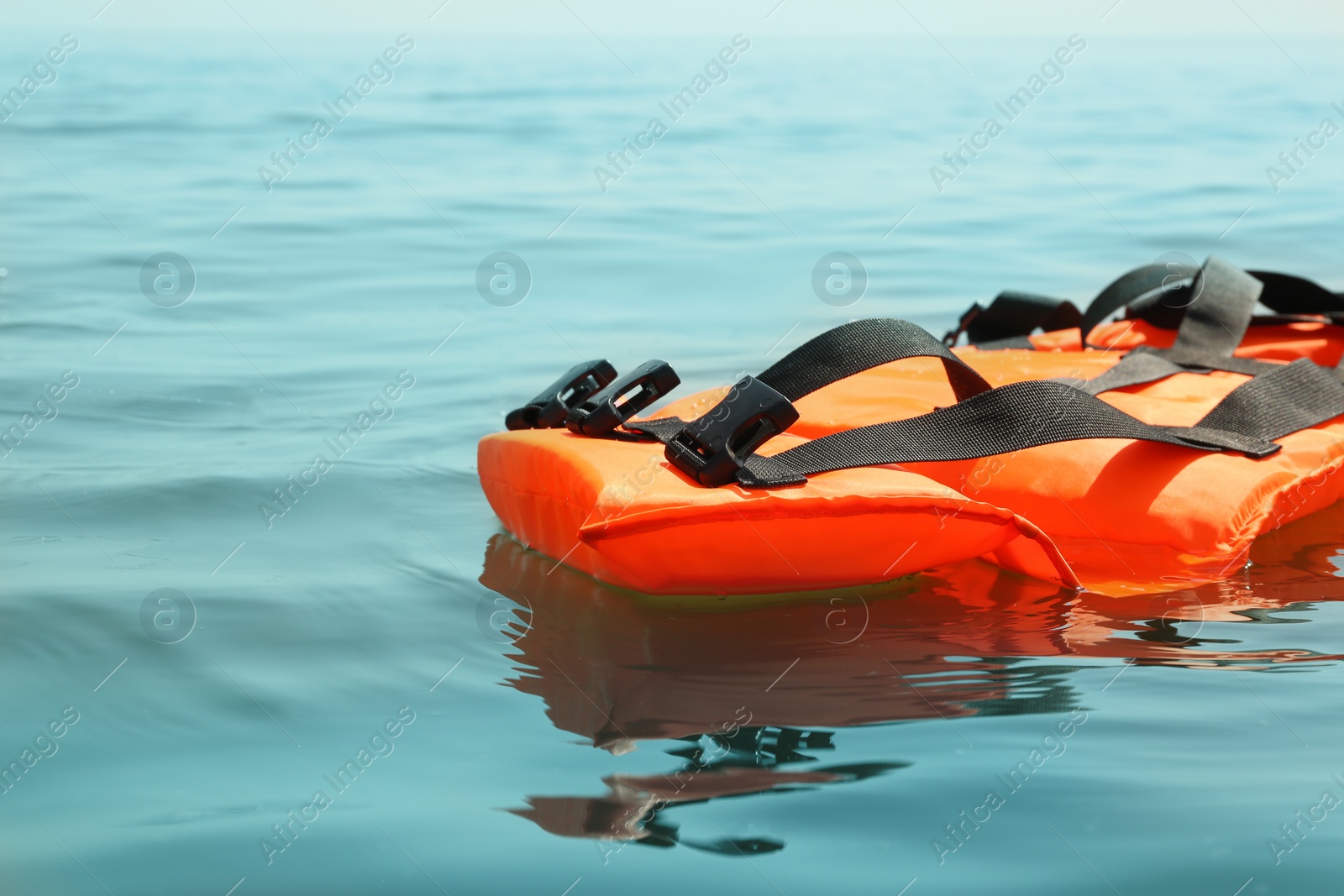 Photo of Orange life jacket floating in sea. Emergency rescue equipment