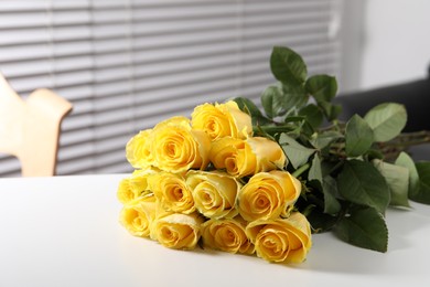 Beautiful bouquet of yellow roses on white table indoors