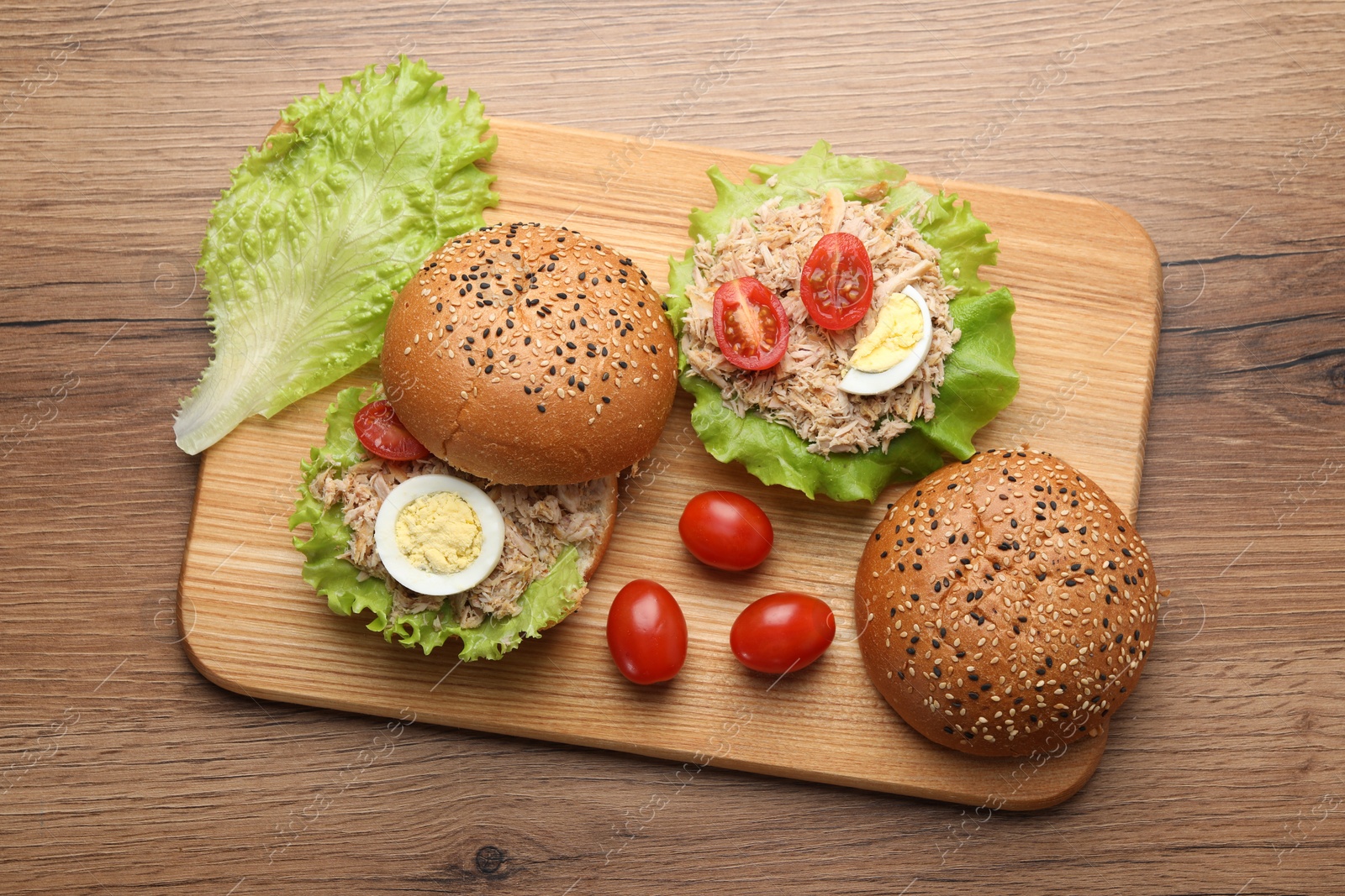 Photo of Delicious sandwiches with tuna, boiled egg and vegetables on wooden table, top view