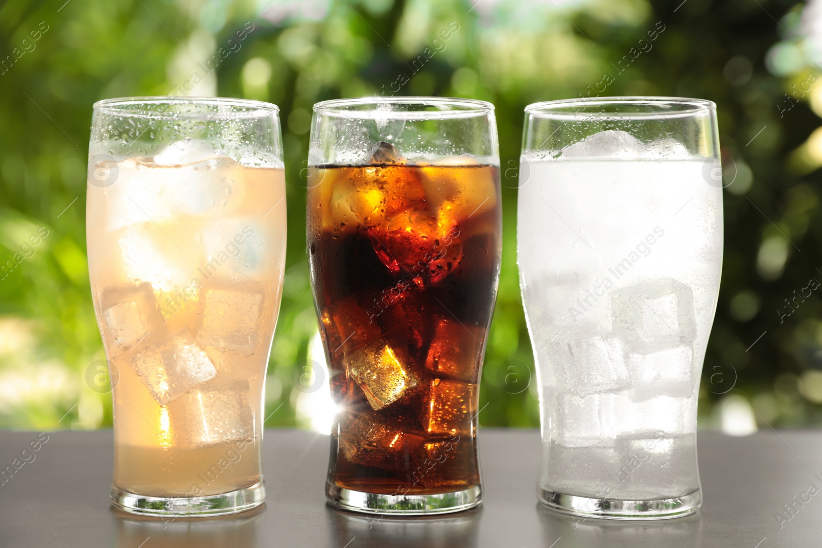 Photo of Delicious refreshing drinks in glasses on grey table outdoors