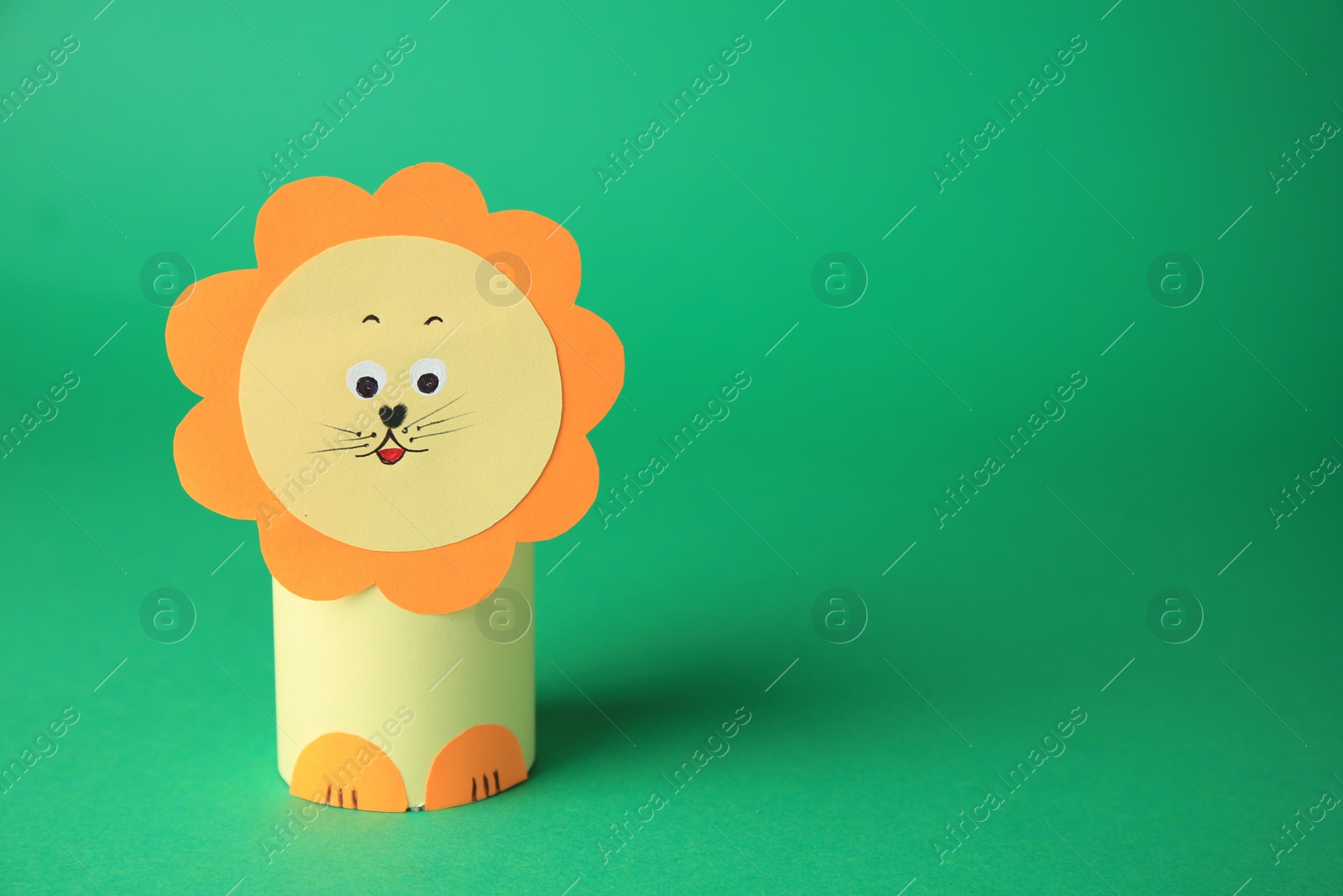 Photo of Toy lion made from toilet paper hub on green background, space for text. Children's handmade ideas