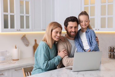 Photo of Happy family with laptop at white table indoors. Space for text