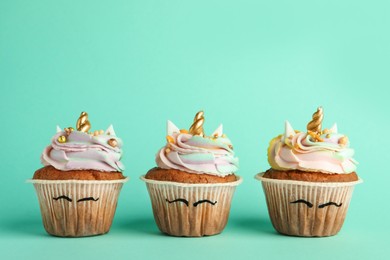 Photo of Cute sweet unicorn cupcakes on turquoise background