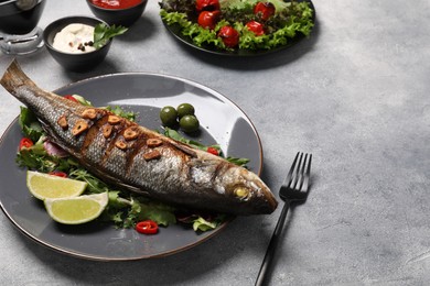 Photo of Delicious sea bass fish and ingredients served on light grey table