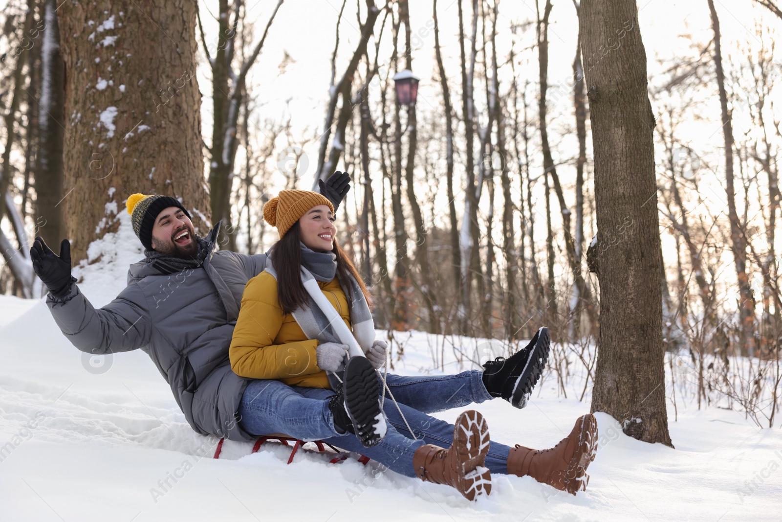 Photo of Happy young couple sledding outdoors on winter day