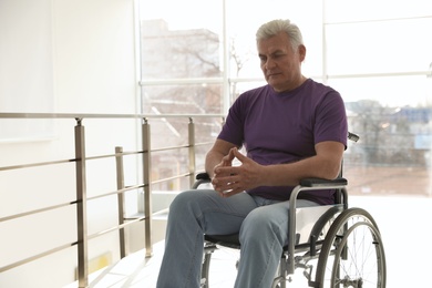 Senior man sitting in wheelchair near window at home
