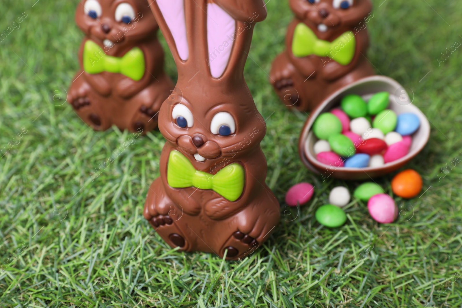 Photo of Easter celebration. Cute chocolate bunnies and egg with colorful candies on green grass