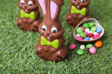 Photo of Easter celebration. Cute chocolate bunnies and egg with colorful candies on green grass