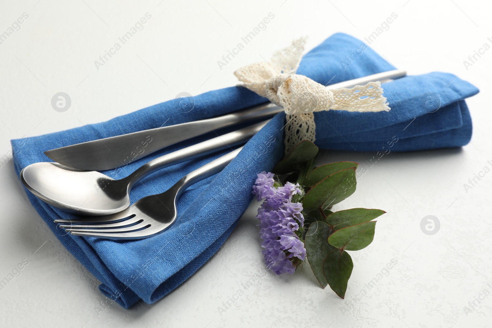 Photo of Stylish setting with cutlery and napkin on white textured table