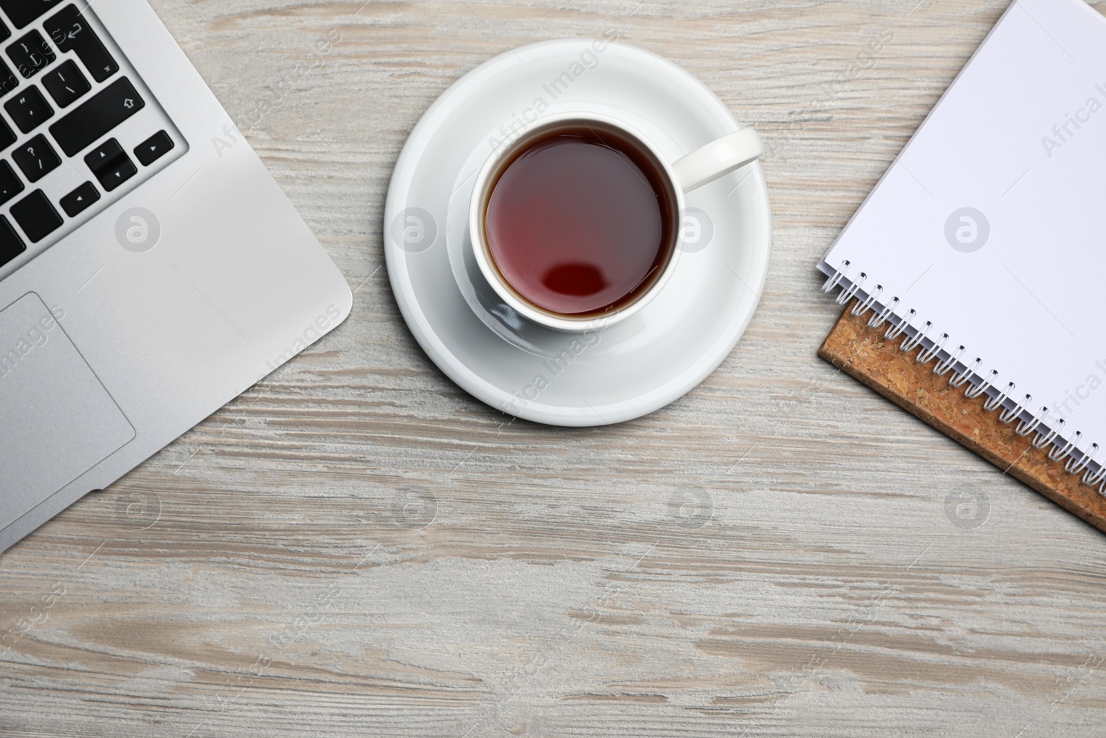 Ceramic mug of aromatic tea, laptop and notebooks on white wooden table, flat lay Photo of Ceramic mug of aromatic tea, laptop and notebooks on white wooden table, flat lay