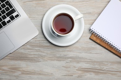 Photo of Ceramic mug of aromatic tea, laptop and notebooks on white wooden table, flat lay