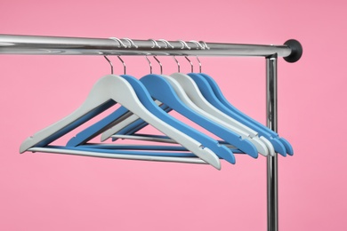 Photo of Empty clothes hangers on metal rack against color background