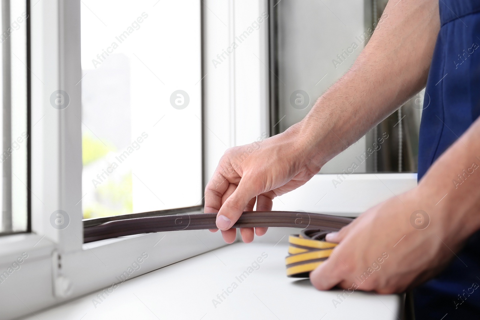 Photo of Construction worker putting sealing foam tape on window indoors