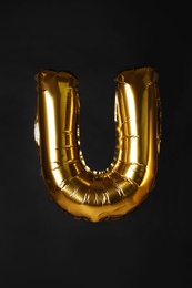 Photo of Golden letter U balloon on black background