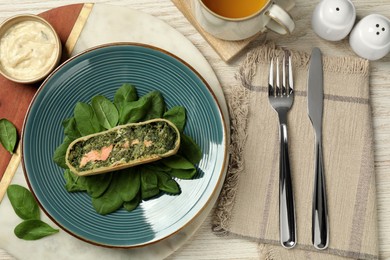 Photo of Piece of delicious strudel with salmon and spinach served on light wooden table, flat lay