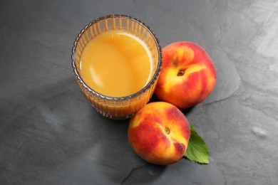 Photo of Glass of delicious peach juice and fresh fruits on black table, above view