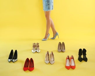 Woman trying on different high heel shoes on yellow background, closeup
