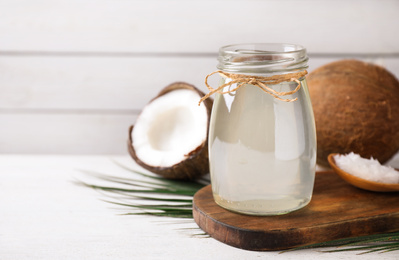 Photo of Coconut oil on white wooden table. Space for text